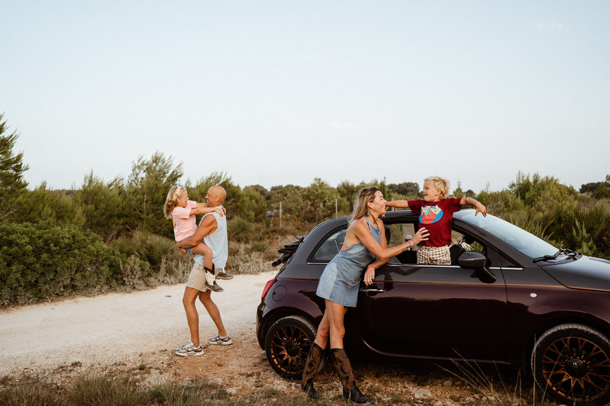 Natural outdoor family portrait of parents and two children in the car at the Montgo Mountain park in Javea, Alicante Spain
