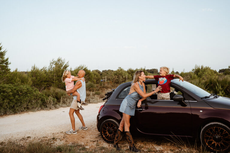 Natural outdoor family portrait of parents and two children in the car at the Montgo Mountain park in Javea, Alicante Spain